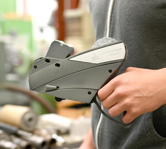 Person holding Meto Industry price labeler in hand – reliable handheld labeler for precise industrial labeling